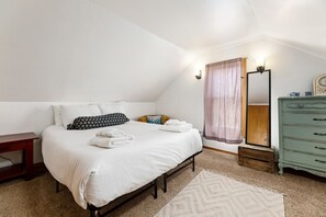 Um quarto com uma cama, cômoda, espelho e mesa de cabeceira.