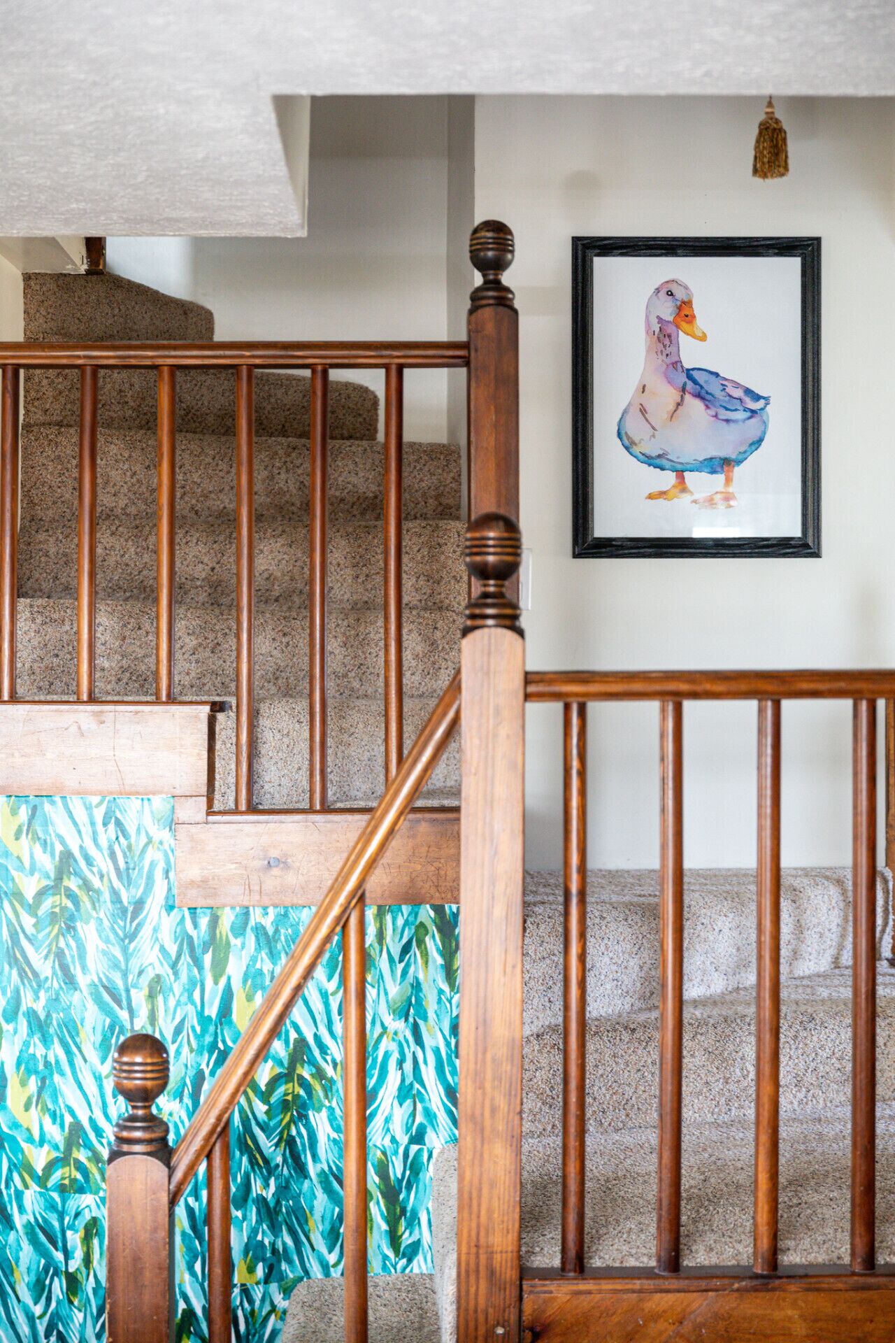 Un escalier en bois, avec un tableau encadré représentant un canard accroché au mur.