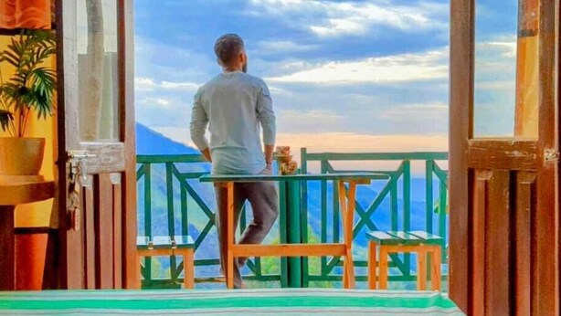 A man standing on a balcony with a view of the sky and mountains. - Misty Cabins Ella (Ella)