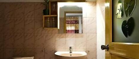 A small bathroom with a toilet, sink, and a mirror.