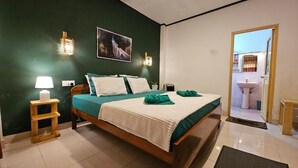 A bedroom with a bed, bedside table, lamp, wall art, and a view of the bathroom through an open door. - Misty Cabins Ella (Ella)