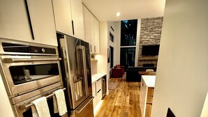Una cocina moderna con electrodomésticos de acero inoxidable, suelo de madera y chimenea de piedra.