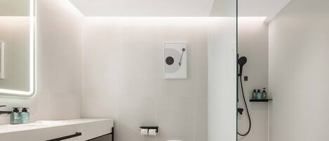 Et moderne badeværelse med toilet, vask med spejl og bruseområde.