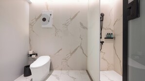 Un baño moderno con inodoro, ducha y paredes de mármol.