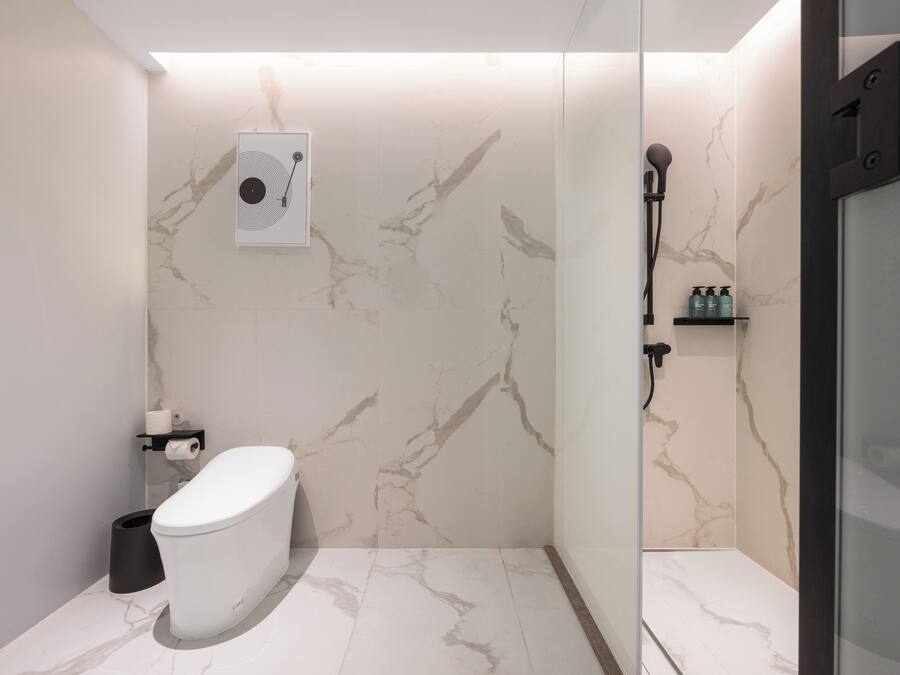 Un baño moderno con inodoro, ducha y paredes de mármol.