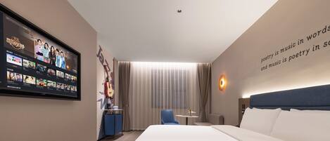 A modern hotel room with a large bed, a flat-screen TV mounted on the wall, a desk with a chair, and a window with curtains.
