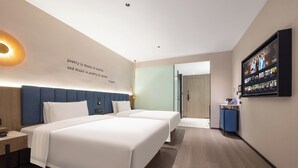 Una habitación de hotel moderna con dos camas, un televisor grande y una cita en la pared sobre poesía y música.