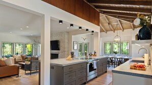 Una cocina moderna con una isla grande, electrodomésticos integrados y un comedor con vistas al exterior.