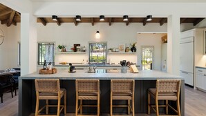 Una cocina amplia con una isla grande, sillas de madera y un diseño moderno.