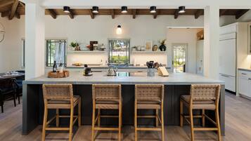 A spacious kitchen with a large island, wooden chairs, and a modern design.