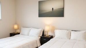 Une chambre d’hôtel avec deux lits, chacun doté d’une table de chevet et d’une lampe, et un grand tableau accroché au mur.