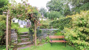 Ein Garten mit einer hölzernen Bank, Steinstufen und einer Steinmauer.