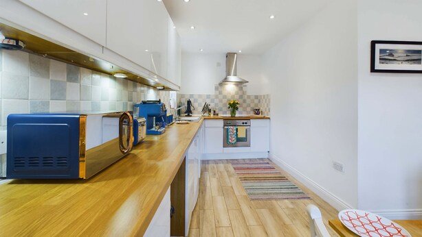 Een moderne keuken met een houten aanrechtblad, ingebouwde apparatuur en een betegelde spatwand.