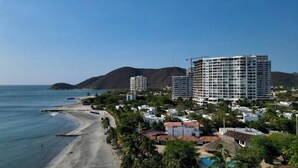 A coastal hotel with multiple buildings, a beach, and mountains in the background.