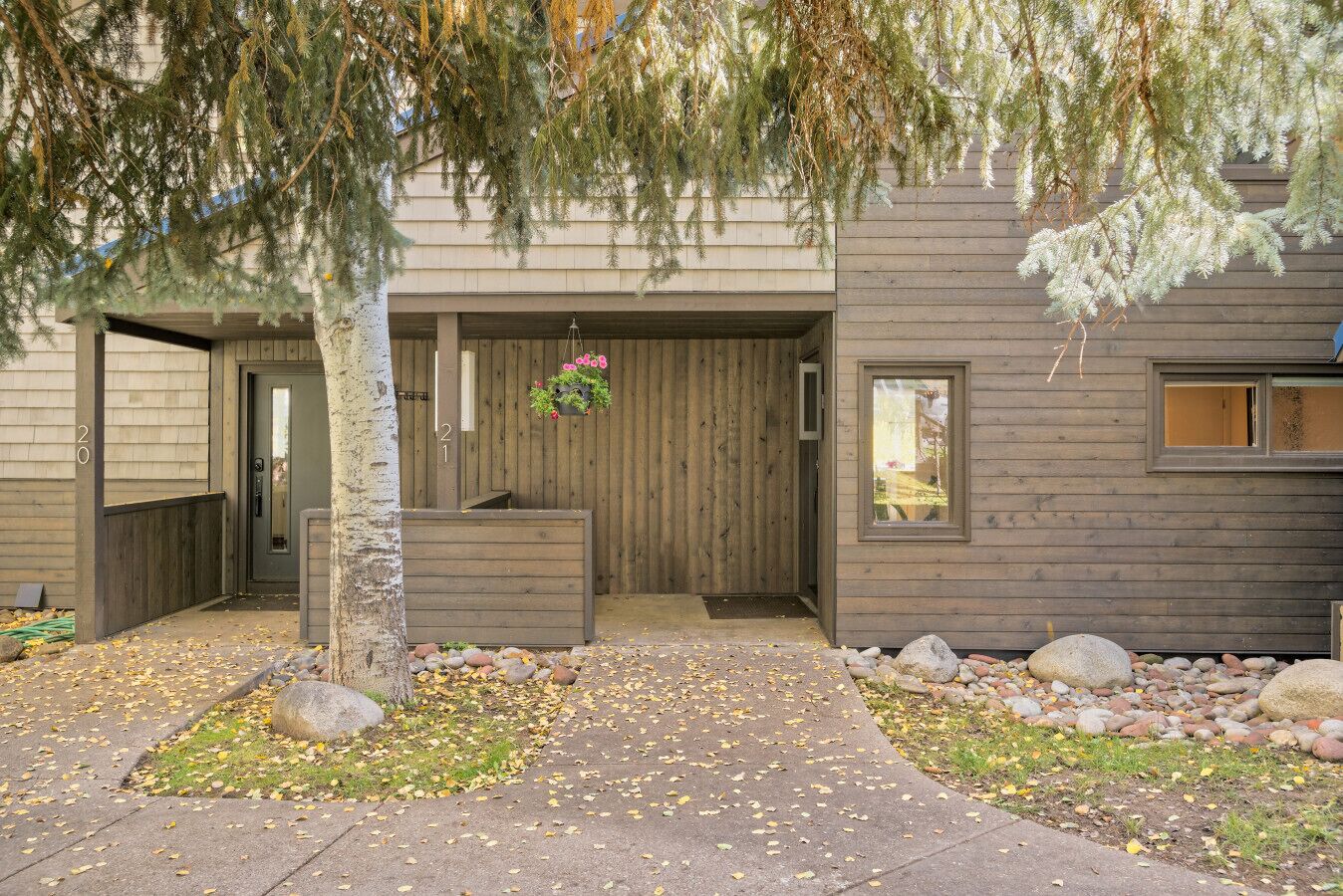 A modern house with a wooden exterior, a front porch, and a stone pathway.