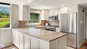 A modern kitchen with granite countertops, stainless steel appliances, and white cabinetry.