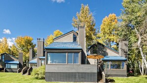 A modern house with a large window, a chimney, and a blue roof.