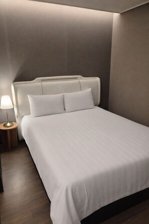A modern hotel room with a large bed, a bedside table with a lamp, and a wooden floor. - Haeundae Elbonz (Busan)