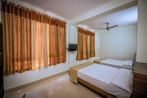 Une chambre d’hôtel avec deux lits, un ventilateur de plafond et des rideaux.
