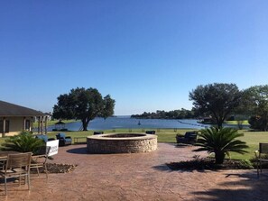A patio area with a stone fire pit, outdoor seating, and a view of a lake. - Stylish Studio on Lake Conroe (Montgomery)
