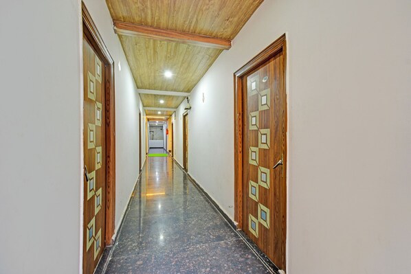A long, narrow hallway with wooden doors on either side, leading to a room at the end. - Fabhotel Dolce Vita Grand (Hyderabad)