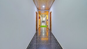 A long, narrow hallway with a polished black floor, wooden ceiling, and white walls. - Fabhotel Dolce Vita Grand (Hyderabad)