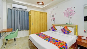 A hotel room with a bed, a desk, a chair, a ceiling fan, and a wall with decorative stickers. - Fabhotel Dolce Vita Grand (Hyderabad)