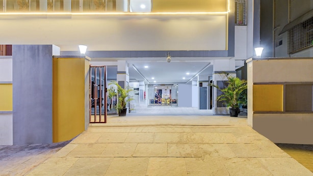 A spacious indoor corridor with a tiled floor, leading to a brightly lit area with a seating arrangement. - FabHotel R3 Atmos - Near Hitech Exibition Centre, Hitech City (Hyderabad)