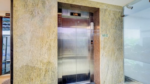 An elevator with a "Lift" sign, a fire exit sign, and a textured wall. - FabHotel R3 Atmos - Near Hitech Exibition Centre, Hitech City (Hyderabad)