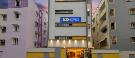 A modern multi-story hotel with a prominent 'fabHOTELS' sign, featuring a clean, contemporary design with a flat roof and a central entrance.
