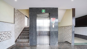 Elevatorindgang med skilt nummer 2, et rygeforbudsskilte og et skilt vedrørende brandsikkerhed.
