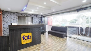 A hotel reception area with a modern design, including a reception desk, a sofa, and a large window offering a view of the outside.