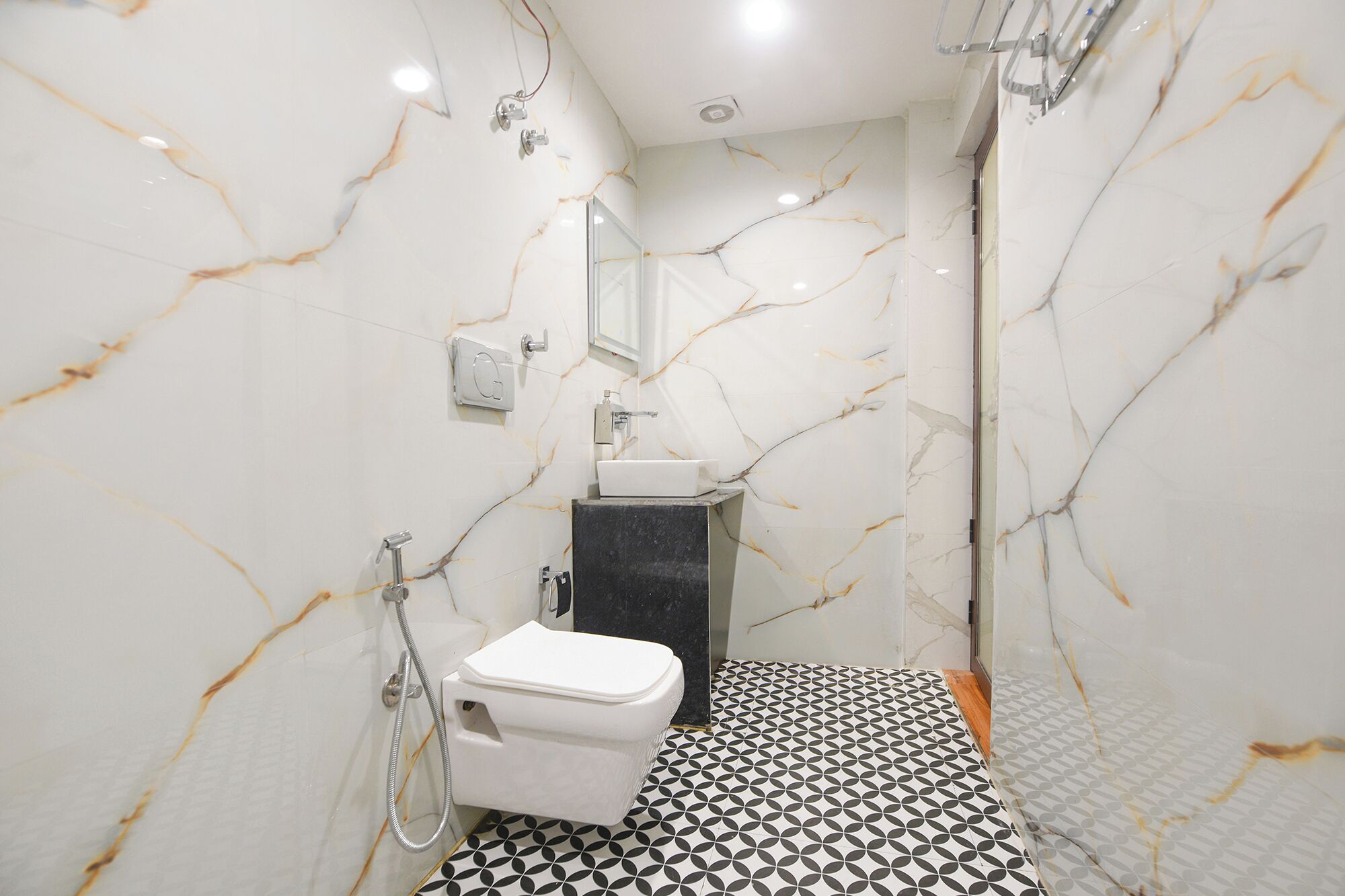 A bathroom with white marble walls, a black sink, and a white toilet.