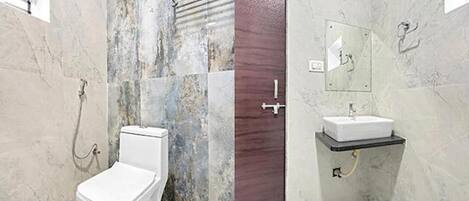 A bathroom with a toilet, shower, and sink.