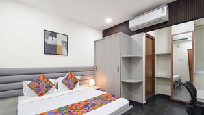 A hotel room with a bed, a bedside table, a lamp, an air conditioner, a wardrobe, a mirror, and a chair. - Fabhotel Yendluri'S Abode (Hyderabad)