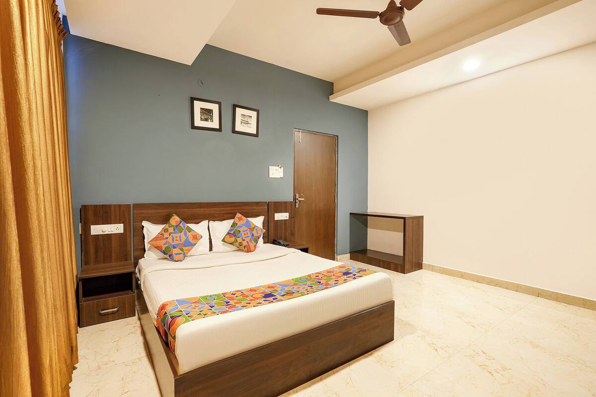 A bedroom with a bed, a nightstand, a dresser, a ceiling fan, and a door.