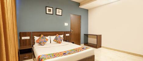A bedroom with a bed, a nightstand, a dresser, a ceiling fan, and a door.