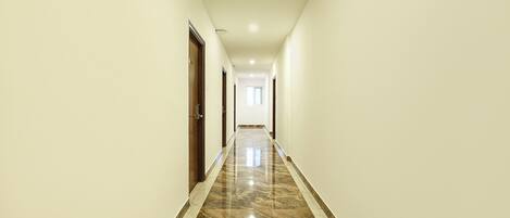 A long, narrow hallway with a polished marble floor and white walls.