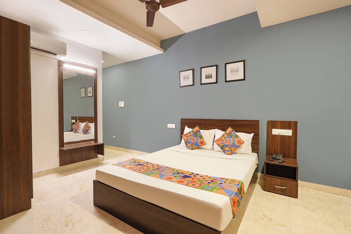 A bedroom with a bed, a nightstand, a mirror, and a ceiling fan.