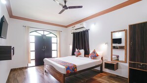A bedroom with a bed, a ceiling fan, an air conditioning unit, a mirror, and a wardrobe. - Via Romeo's Stay - A Beach Property (Calangute)