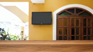 A room with a wooden door, a mounted TV, and a map on the wall. - Via Romeo's Stay - A Beach Property (Calangute)