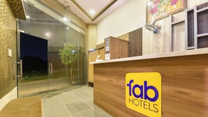 Een receptie met een houten balie, een glazen deur en een bordje met de tekst 'fab hotels'.