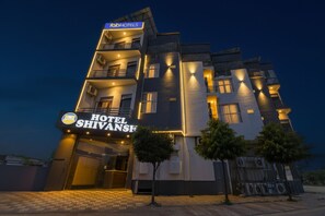 Een meerhoog hotel met een bord waarop 'Hotel Shivansh' staat.