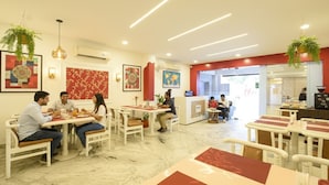 Un restaurante con suelo de mármol, mobiliario blanco y detalles en rojo.