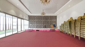 Una habitación amplia con alfombra roja, un escenario con fondo rosa y una pared decorativa con un diseño geométrico.