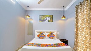 A bedroom with a bed, two wall-mounted lamps, a framed picture, and a patterned curtain. - Fabhotel Galaxy Grand (Panvel)