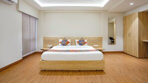 Ein modernes Hotelzimmer mit einem großen Bett, einem Holz-Kopfteil und einem eingebauten Kleiderschrank.