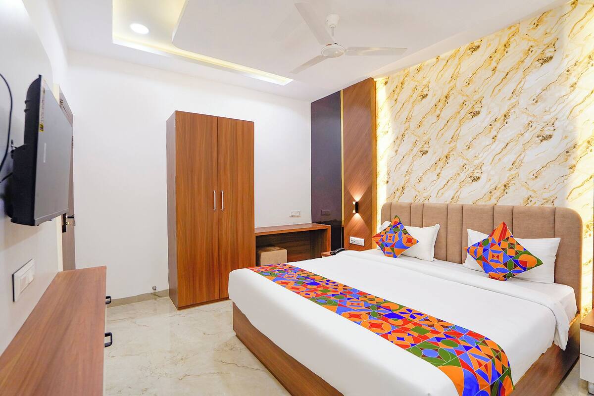 Una habitación de hotel con cama, escritorio, armario y ventilador de techo.