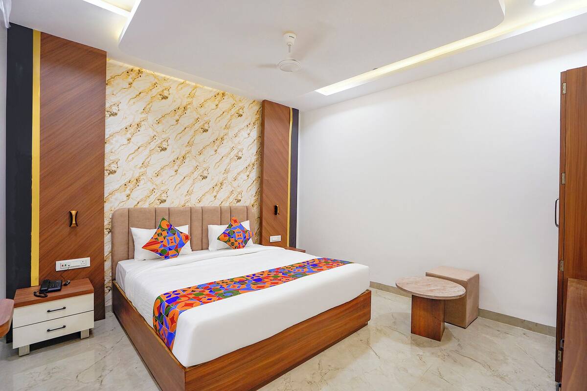 Un dormitorio moderno con una cama grande, mesitas de noche, un pequeño armario y una mesita redonda.