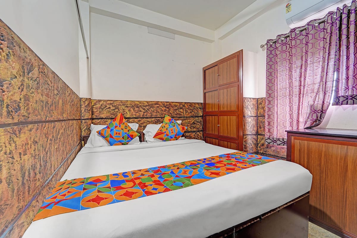 A bedroom with a bed, a wooden wardrobe, and a patterned curtain.